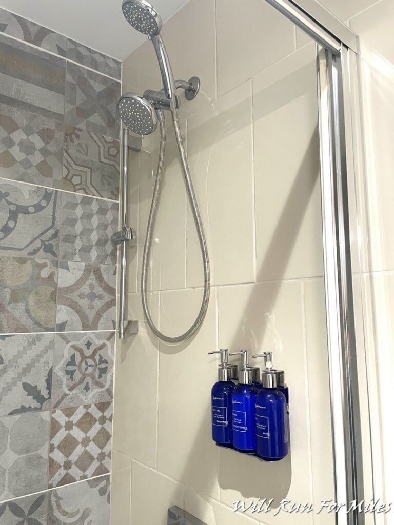 a shower head with blue bottles on the wall