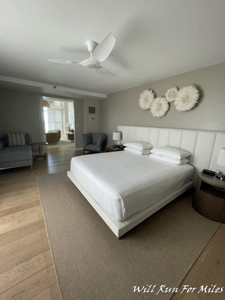 a bedroom with a white bed and a white fan