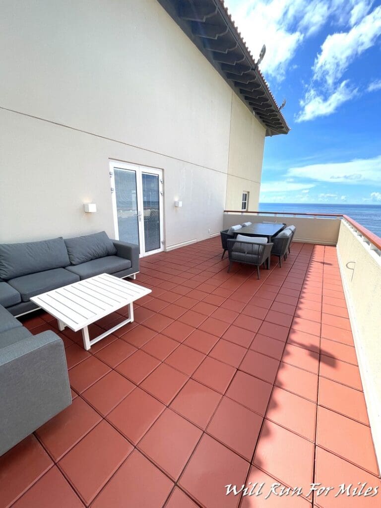 a patio with a table and chairs on a balcony overlooking the ocean