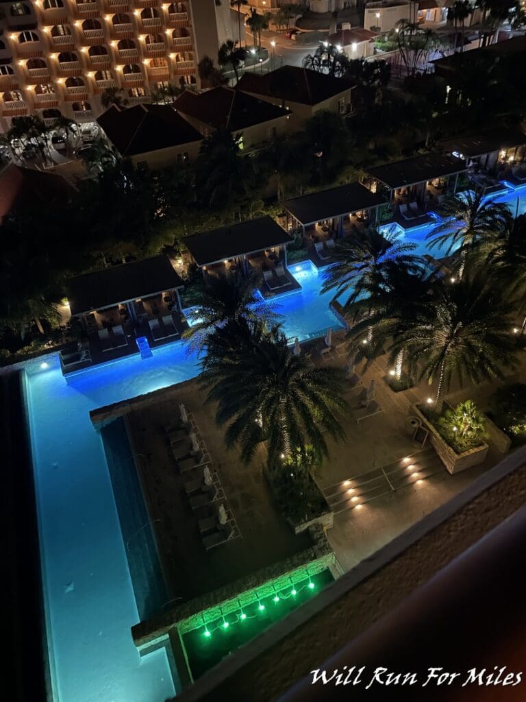 a pool with palm trees and buildings at night