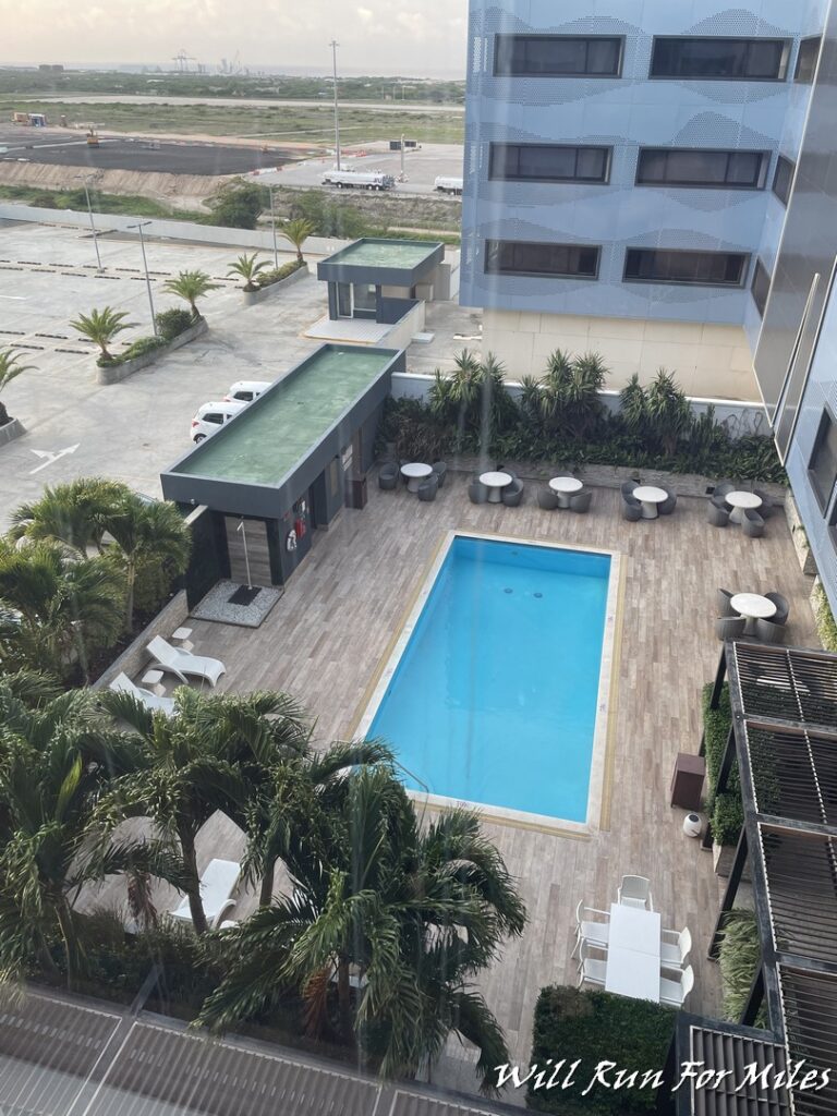 a pool and a building with trees and cars