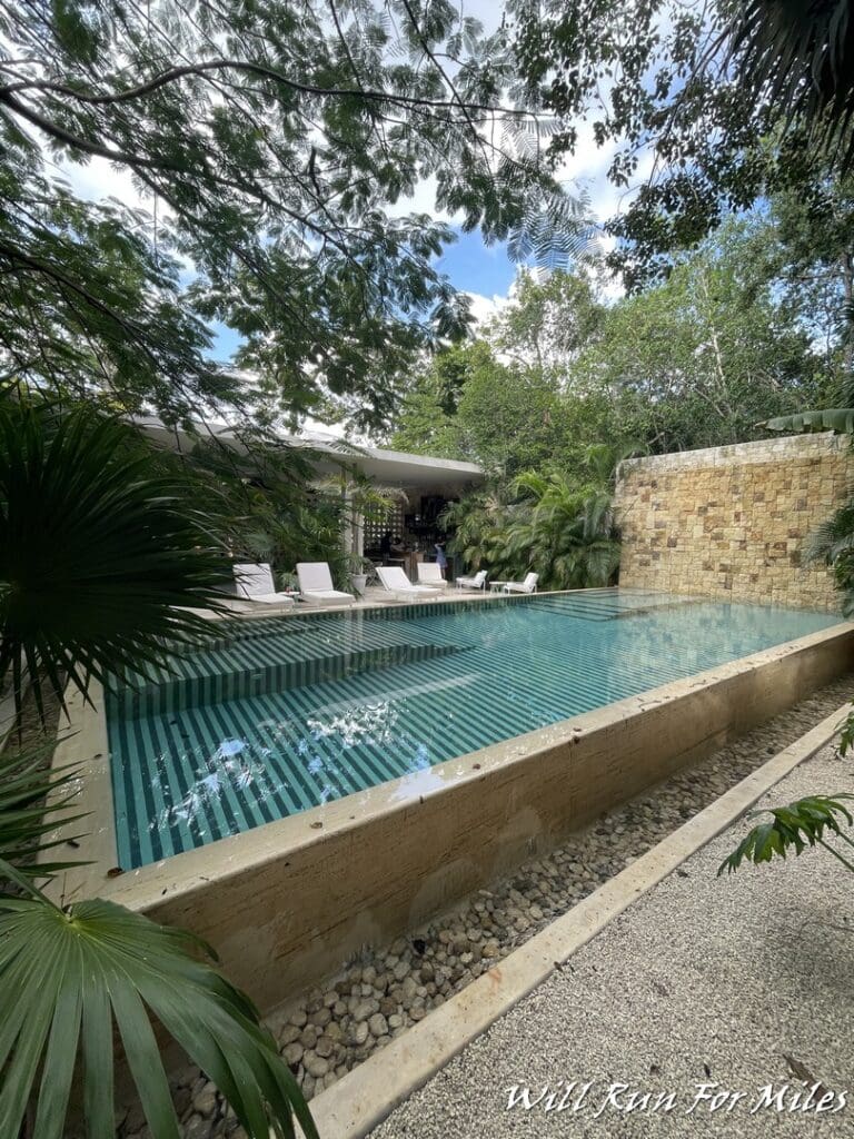 a pool with a stone wall and chairs