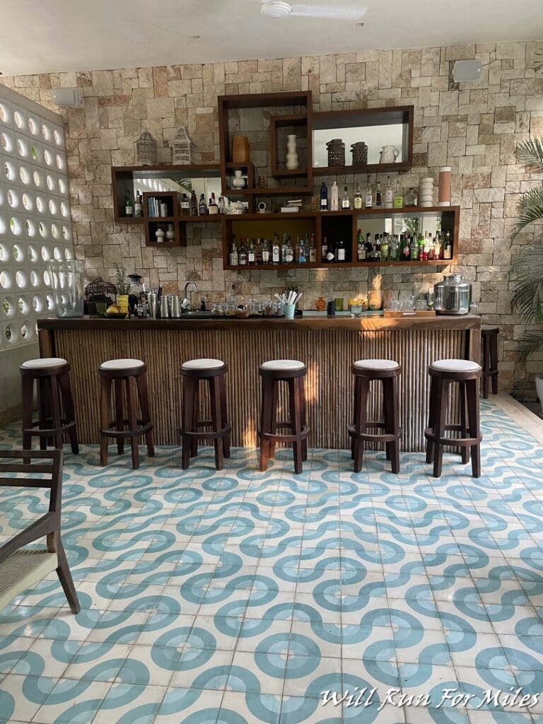 a bar with stools and shelves in front of a wall