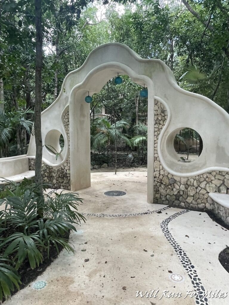 a stone archway with round holes and a chain in the middle of a park