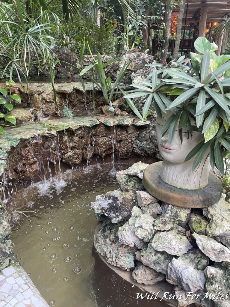 a fountain with a head planter and a small stream