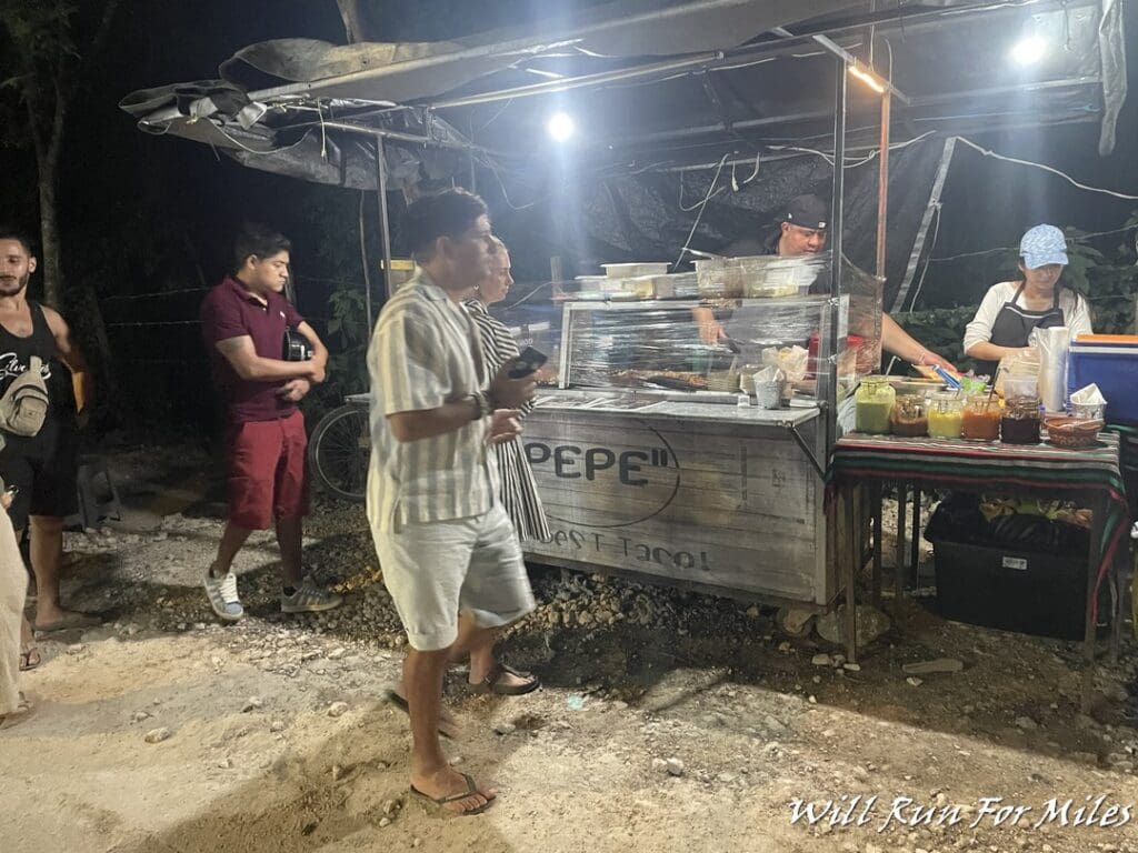 a group of people standing next to a food cart