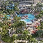 a pool and palm trees with a slide and a building