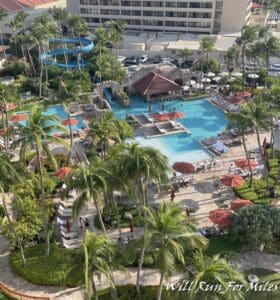 a pool and palm trees with a slide and a building