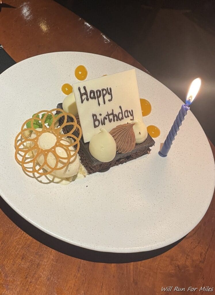 a plate with a piece of cake and a lit candle