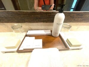 a bathroom counter with a mirror and a tray of soap and a bottle of shampoo