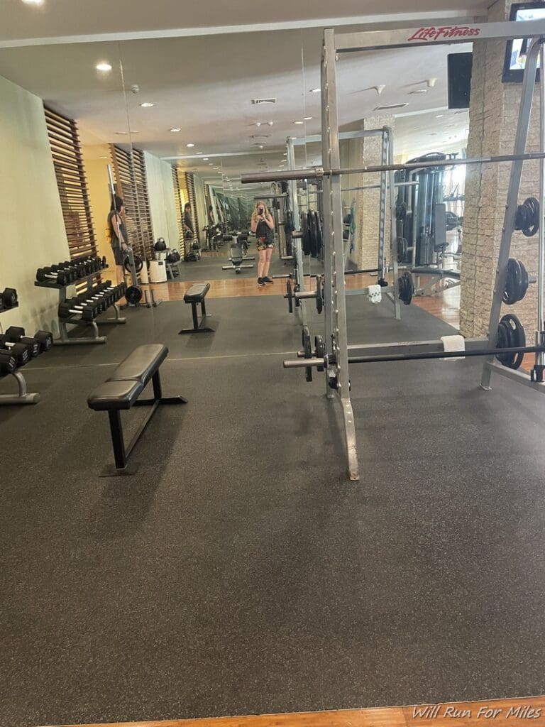 a gym with weights and a woman standing in front of them