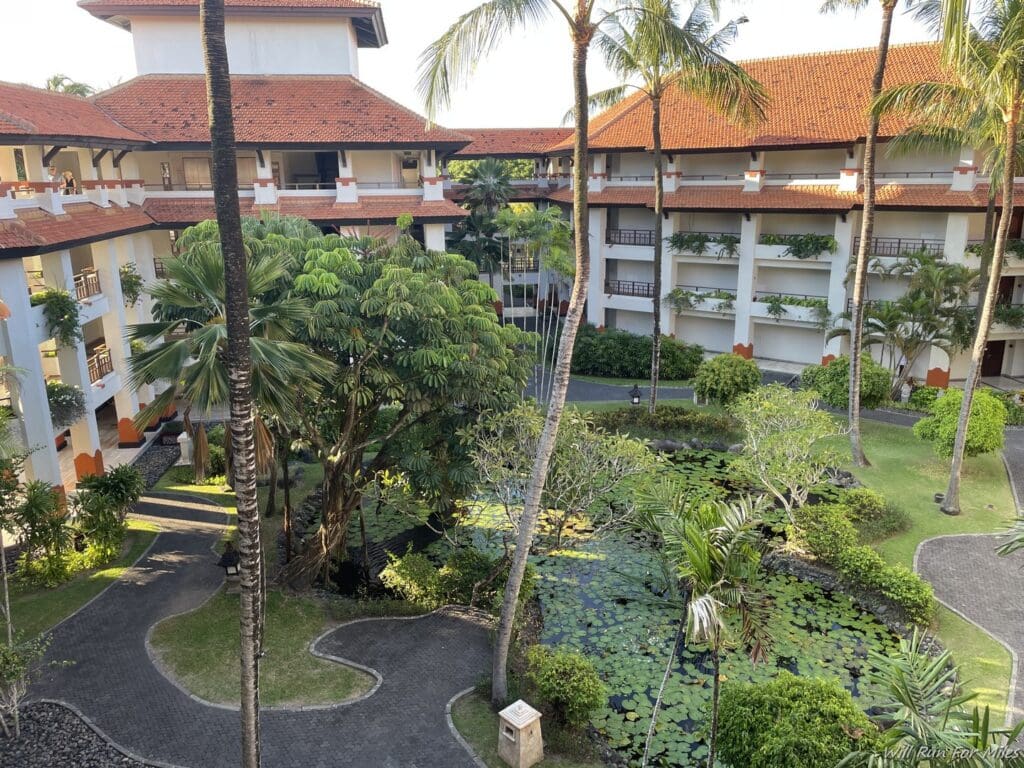 a courtyard with trees and a pond in front of a building