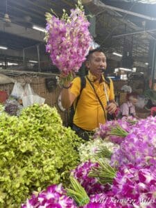 a man holding flowers in a market