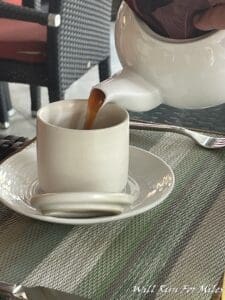 a teapot pouring brown liquid into a cup