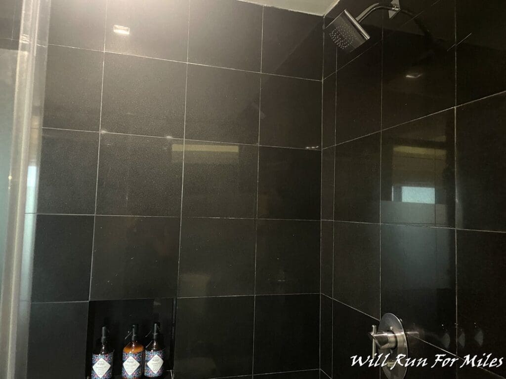a shower with black tile walls