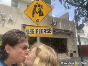 a man and woman kissing in front of a sign
