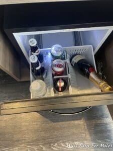 a mini fridge with bottles of beer and cans