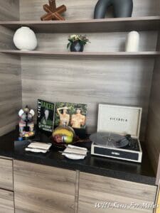 a shelf with a record player and a bowl of fruit
