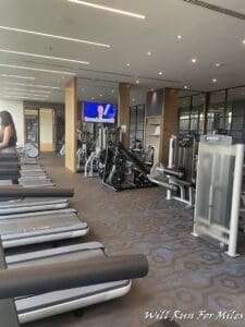 a room with several treadmills and a woman sitting on a chair