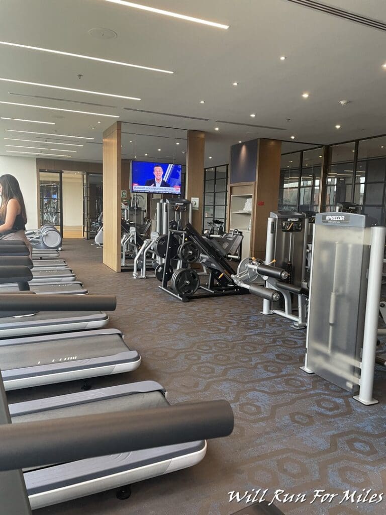 a room with several treadmills and a woman sitting on a chair