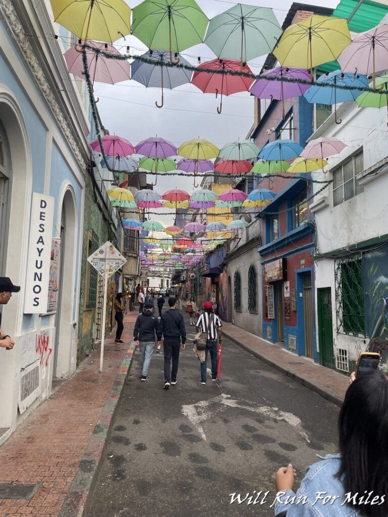a group of people walking down a street with colorful umbrellas