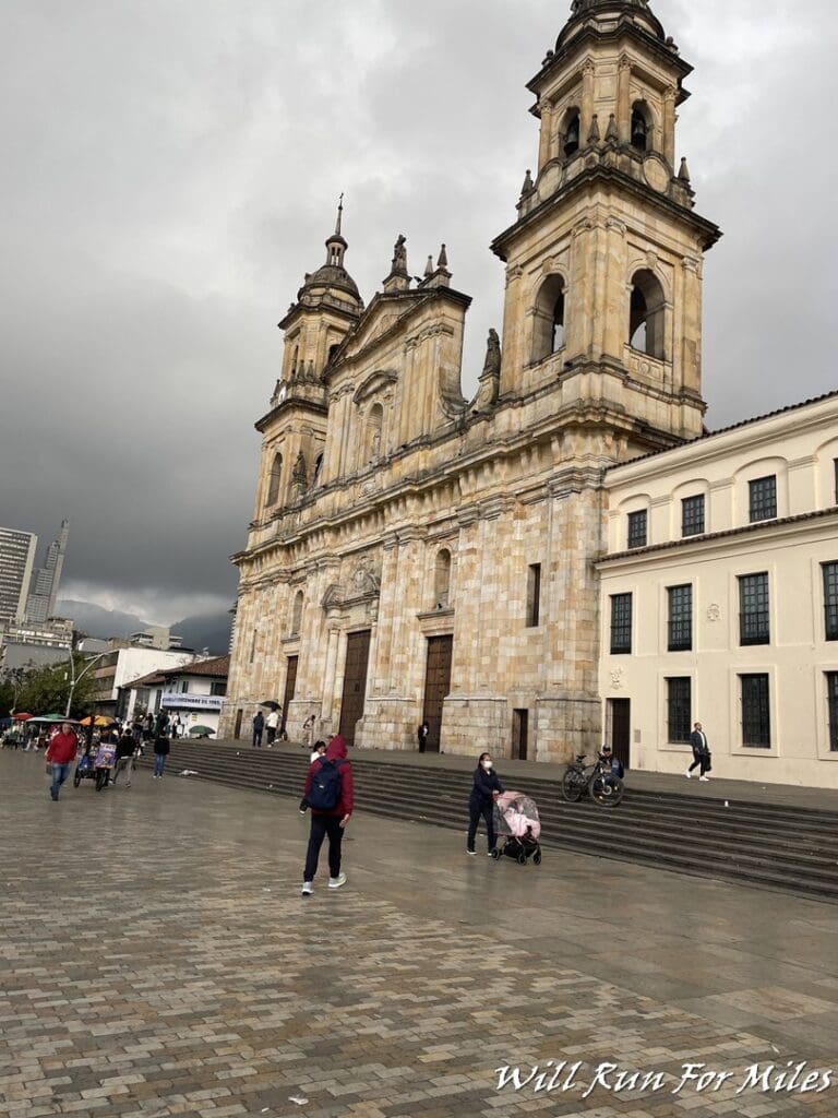 a stone building with a tower and people walking in front of it