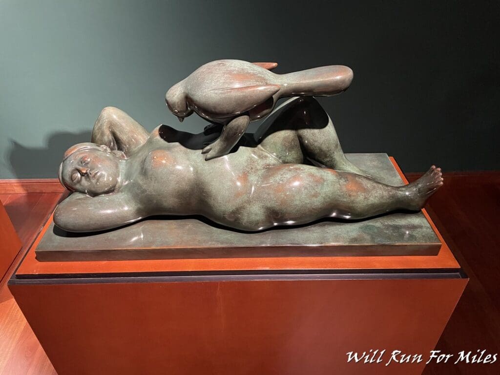 a statue of a woman lying down with a bird on her back